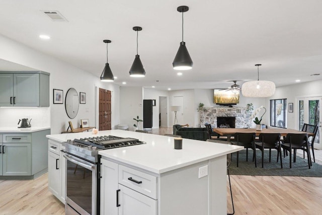 3902 Knollwood Dr Unit A, Austin, TX 78731 - kitchen with stainless steel range with gas cooktop, light wood-style floors, a center island, a fireplace, and decorative backsplash