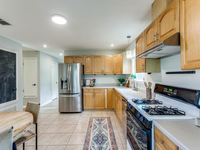 1705 Adriane Dr, Austin, TX 78721 - kitchen with range with gas stovetop, stainless steel fridge, under cabinet range hood, a sink, and light tile patterned floors