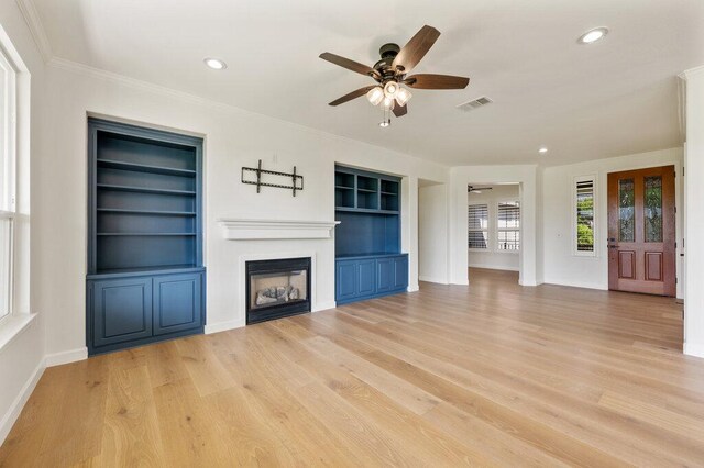 110 Chuckwagon Trl, Georgetown, TX 78633 - unfurnished living room with ceiling fan, built in shelves, a glass covered fireplace, recessed lighting, and crown molding