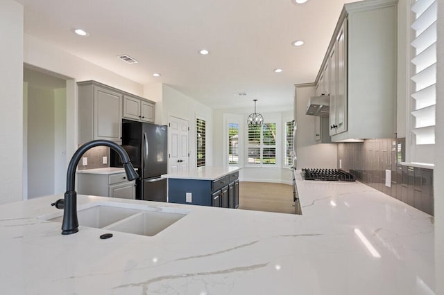 110 Chuckwagon Trl, Georgetown, TX 78633 - kitchen featuring gray cabinetry, freestanding refrigerator, ventilation hood, recessed lighting, and tasteful backsplash