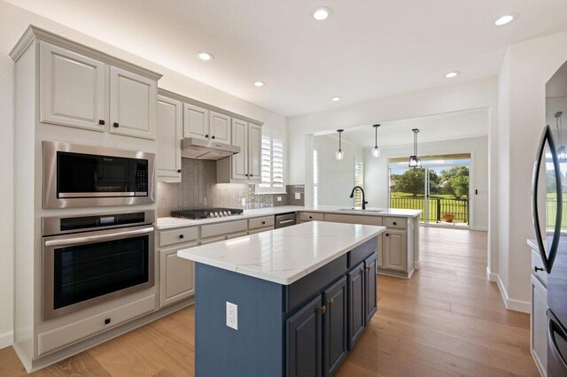 110 Chuckwagon Trl, Georgetown, TX 78633 - kitchen featuring stainless steel appliances, a peninsula, backsplash, a kitchen island, and light wood finished floors