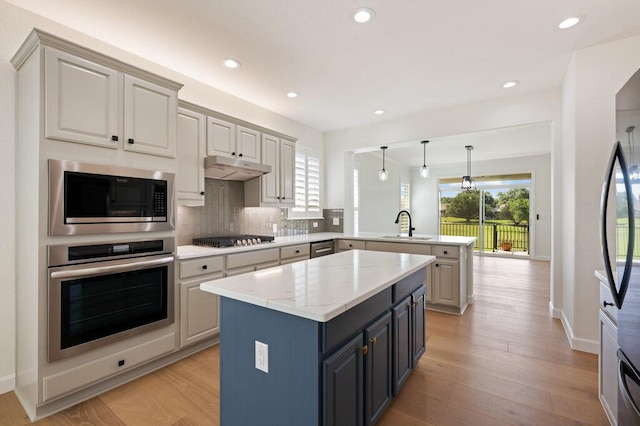 110 Chuckwagon Trl, Georgetown, TX 78633 - kitchen with appliances with stainless steel finishes, a peninsula, backsplash, a center island, and light wood finished floors