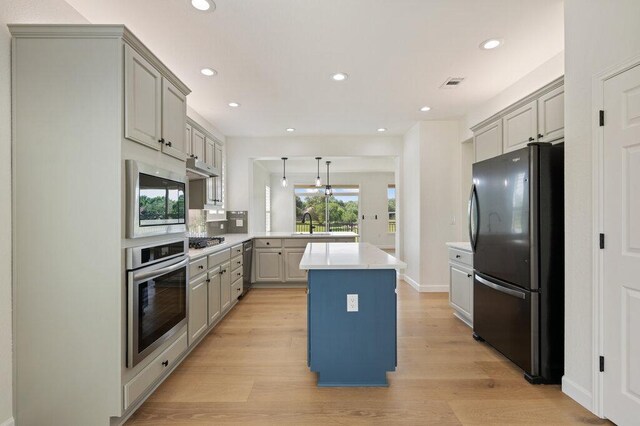 110 Chuckwagon Trl, Georgetown, TX 78633 - kitchen with appliances with stainless steel finishes, gray cabinets, a peninsula, light countertops, and a kitchen island