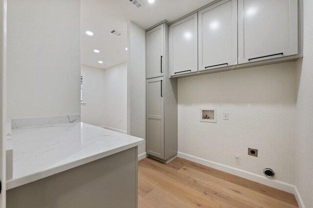 110 Chuckwagon Trl, Georgetown, TX 78633 - laundry room featuring electric dryer hookup, cabinet space, light wood-style flooring, baseboards, and hookup for a washing machine