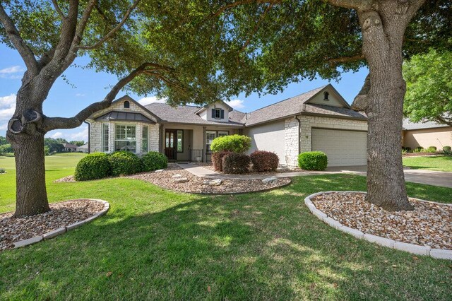 110 Chuckwagon Trl, Georgetown, TX 78633 - view of front of house with stone siding, a front yard, an attached garage, and driveway