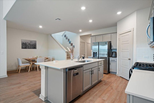 13705 Mc Arthur Dr, Manor, TX 78653 - kitchen featuring appliances with stainless steel finishes, gray cabinetry, a sink, light wood-style flooring, and recessed lighting