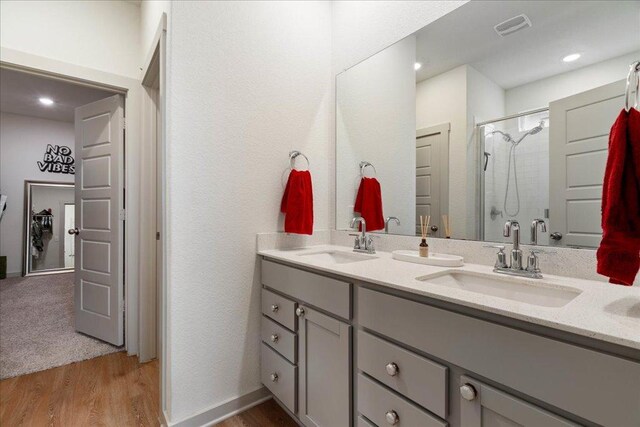 13705 Mc Arthur Dr, Manor, TX 78653 - full bath with double vanity, a shower with shower door, wood finished floors, and recessed lighting