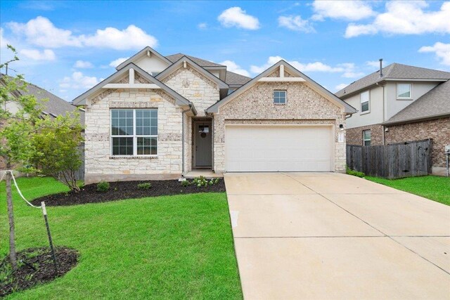 13705 Mc Arthur Dr, Manor, TX 78653 - view of front of house featuring stone siding, an attached garage, and driveway