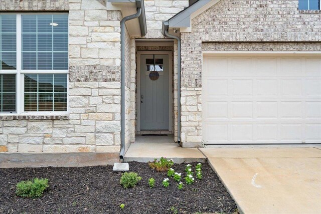 13705 Mc Arthur Dr, Manor, TX 78653 - property entrance featuring stone siding, an attached garage, and driveway