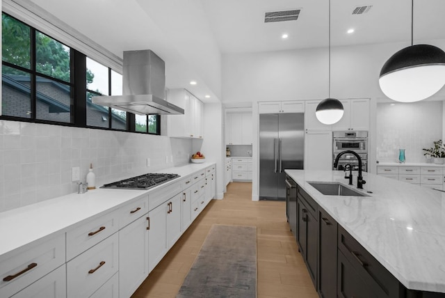 6202 Nasco Dr, Austin, TX 78757 - kitchen with island exhaust hood, a sink, stainless steel appliances, white cabinetry, and tasteful backsplash