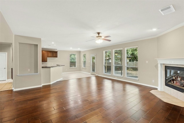 7420 Jaborandi Dr, Austin, TX 78739 - unfurnished living room featuring a tiled fireplace, crown molding, a ceiling fan, dark wood-style flooring, and baseboards