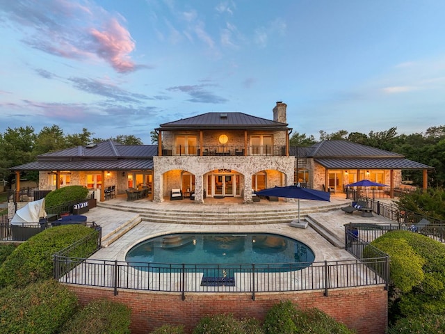 15902 Soleil Ct, Austin, TX 78734 - rear view of house with a standing seam roof, a balcony, a metal roof, a chimney, and a patio area