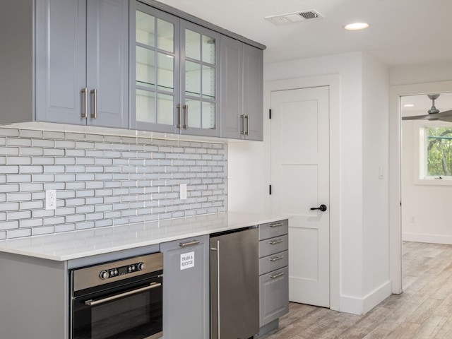 15902 Soleil Ct, Austin, TX 78734 - kitchen featuring oven, gray cabinetry, fridge, backsplash, and light wood-style flooring