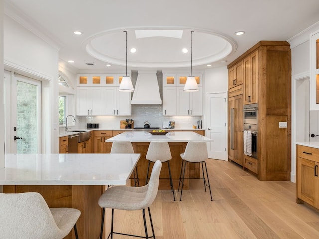 15902 Soleil Ct, Austin, TX 78734 - kitchen featuring custom range hood, light wood-style floors, a kitchen island, glass insert cabinets, and recessed lighting