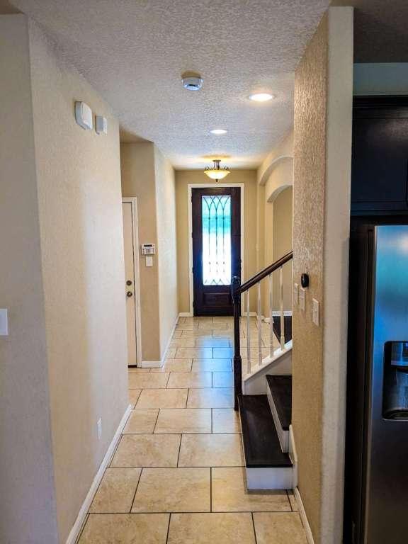 1226 Hidden Cave Dr, New Braunfels, TX 78132 - doorway to outside with a textured ceiling, baseboards, light tile patterned flooring, and stairs