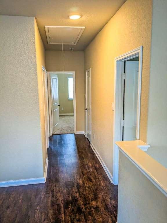 1226 Hidden Cave Dr, New Braunfels, TX 78132 - hallway with attic access, wood finished floors, baseboards, and a textured wall