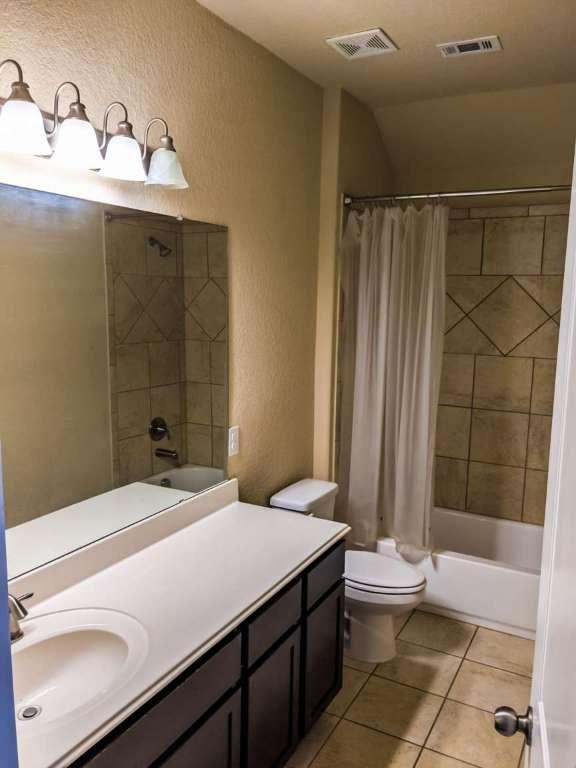 1226 Hidden Cave Dr, New Braunfels, TX 78132 - full bathroom with a textured wall, tile patterned flooring, toilet, shower / tub combo with curtain, and vanity