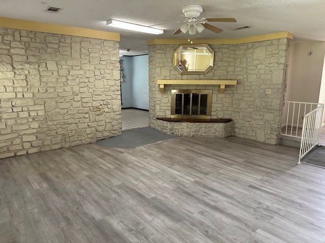 1412 Ocotilla Dr, Marble Falls, TX 78654 - unfurnished living room with a ceiling fan, wood finished floors, a fireplace, and a textured ceiling