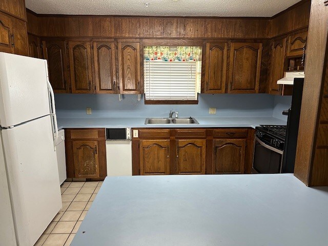 1412 Ocotilla Dr, Marble Falls, TX 78654 - kitchen featuring white appliances, light tile patterned floors, light countertops, a sink, and a textured ceiling
