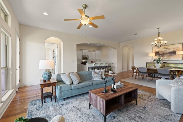 20213 Hidden Gully Ln, Pflugerville, TX 78660 - living room with arched walkways, a ceiling fan, light wood finished floors, a chandelier, and recessed lighting