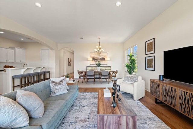 20213 Hidden Gully Ln, Pflugerville, TX 78660 - living room featuring a chandelier, wood finished floors, recessed lighting, arched walkways, and baseboards