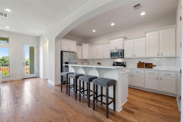 20213 Hidden Gully Ln, Pflugerville, TX 78660 - kitchen featuring stainless steel appliances, arched walkways, light countertops, white cabinetry, and recessed lighting