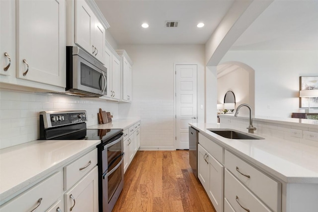 20213 Hidden Gully Ln, Pflugerville, TX 78660 - kitchen with stainless steel appliances, a sink, light wood-style flooring, white cabinetry, and light countertops