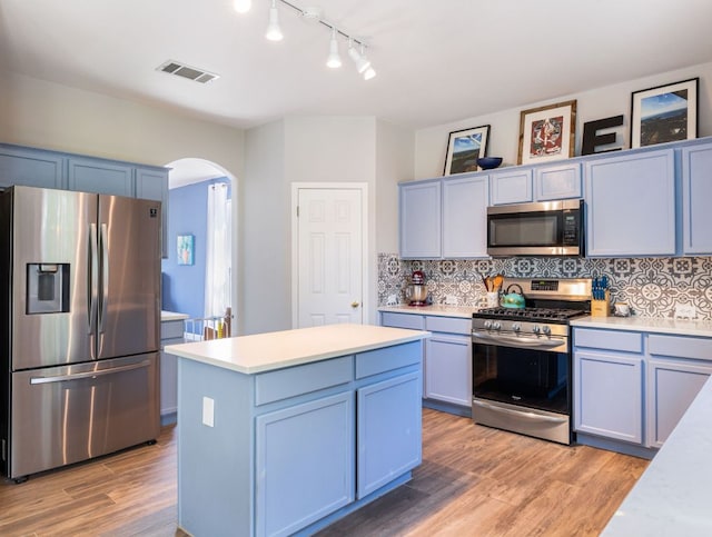 12705 Bransford Cv, Austin, TX 78753 - kitchen featuring appliances with stainless steel finishes, arched walkways, light countertops, light wood finished floors, and tasteful backsplash