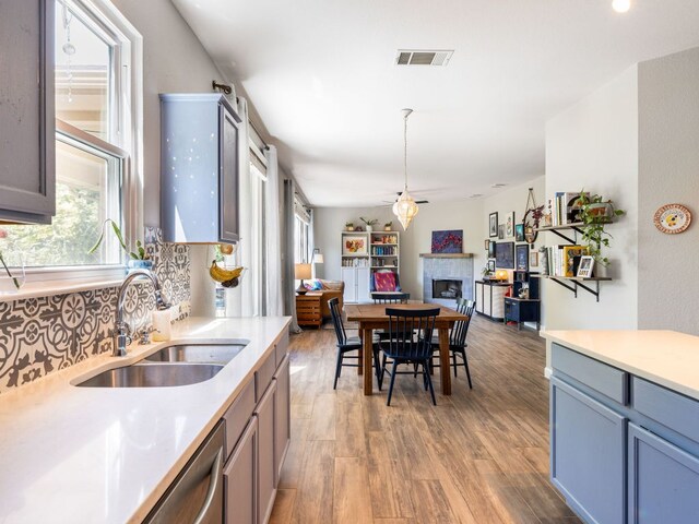12705 Bransford Cv, Austin, TX 78753 - kitchen featuring a sink, a fireplace, open floor plan, tasteful backsplash, and light wood-style flooring