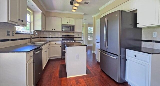 kitchen featuring stainless steel appliances, a sink, dark countertops, white cabinets, and dark wood-style flooring