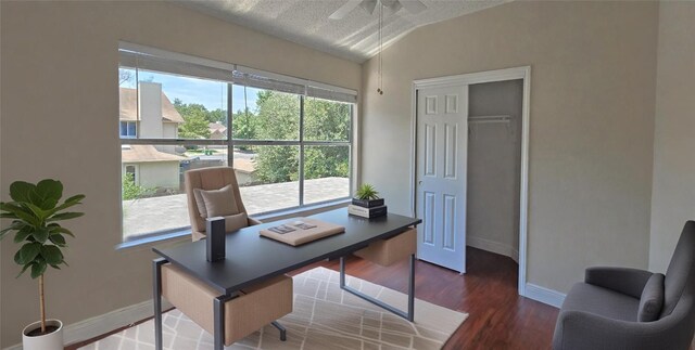 home office featuring lofted ceiling, wood finished floors, ceiling fan, baseboards, and a textured ceiling
