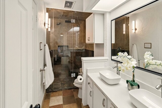 12707 Palfrey Dr, Austin, TX 78727 - full bathroom featuring double vanity, a shower stall, toilet, and stone finish flooring