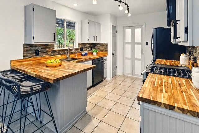 12707 Palfrey Dr, Austin, TX 78727 - kitchen with butcher block counters, black appliances, a sink, decorative backsplash, and light tile patterned floors