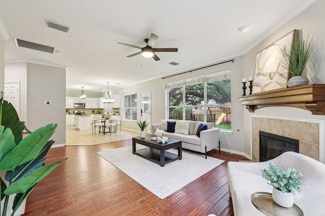10113 Cassandra Dr, Austin, TX 78717 - living area with a ceiling fan, crown molding, a tile fireplace, hardwood / wood-style flooring, and baseboards