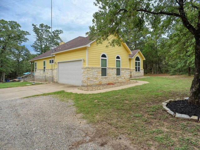 247 Campfire Way, Smithville, TX 78957 - view of front facade featuring driveway, stone siding, a garage, a front yard, and a chimney