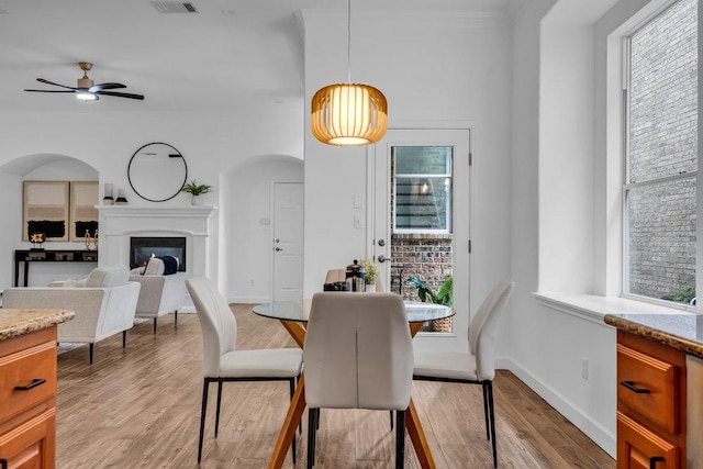 1055 Sunflower Trl, Austin, TX 78745 - dining room with a ceiling fan, light wood-type flooring, a glass covered fireplace, and baseboards