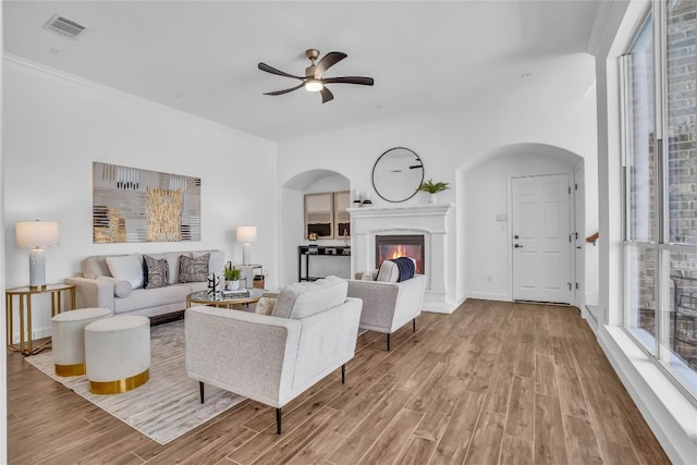 1055 Sunflower Trl, Austin, TX 78745 - living room featuring arched walkways, a ceiling fan, wood finished floors, a glass covered fireplace, and ornamental molding