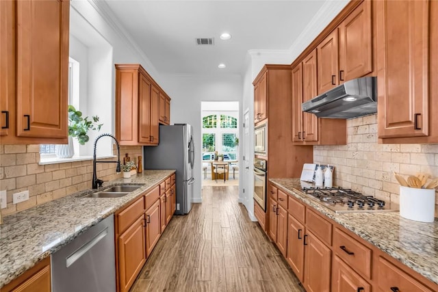 1055 Sunflower Trl, Austin, TX 78745 - kitchen featuring appliances with stainless steel finishes, under cabinet range hood, light stone countertops, backsplash, and light wood finished floors