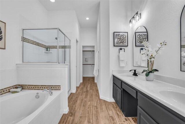 1055 Sunflower Trl, Austin, TX 78745 - bathroom featuring a shower stall, double vanity, a garden tub, wood finished floors, and a walk in closet