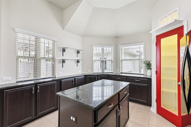 238 Rock Bluff Ln, San Marcos, TX 78666 - kitchen with light tile patterned flooring, dark stone counters, a center island, dark brown cabinetry, and high vaulted ceiling