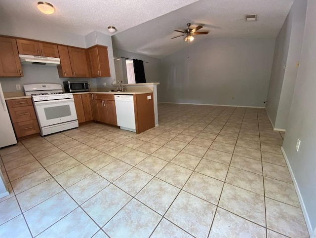1402 Waterloo Trl, Austin, TX 78704 - kitchen featuring white appliances, under cabinet range hood, a peninsula, vaulted ceiling, and light countertops