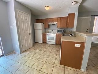 1402 Waterloo Trl, Austin, TX 78704 - kitchen with freestanding refrigerator, stove, a sink, brown cabinets, and stainless steel microwave