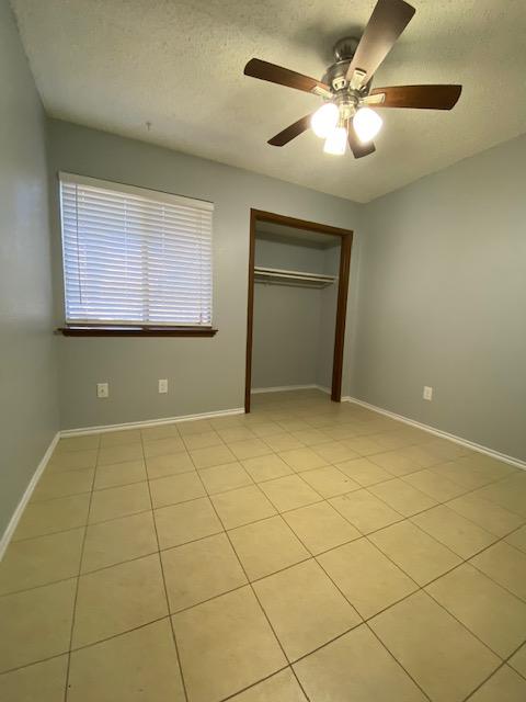 1402 Waterloo Trl, Austin, TX 78704 - unfurnished bedroom with a closet, a textured ceiling, ceiling fan, and light tile patterned flooring