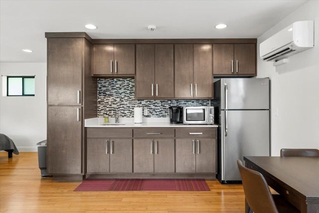 1706 Canterbury St, Austin, TX 78702 - kitchen with appliances with stainless steel finishes, an AC wall unit, a sink, dark brown cabinetry, and light countertops