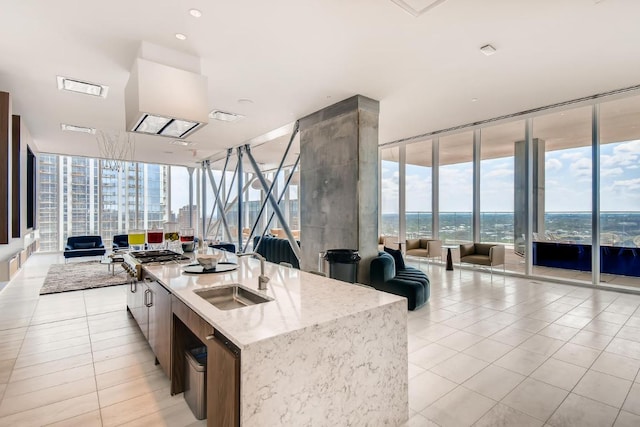 301 W Ave Unit 2003, Austin, TX 78701 - kitchen with open floor plan, a wall of windows, light tile patterned flooring, a sink, and a kitchen island with sink