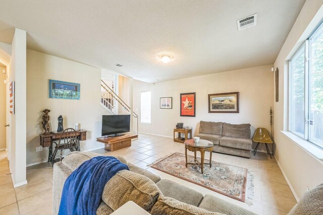 633 Sweet Leaf Ln, Pflugerville, TX 78660 - living room with light tile patterned floors, stairs, baseboards, and a textured ceiling