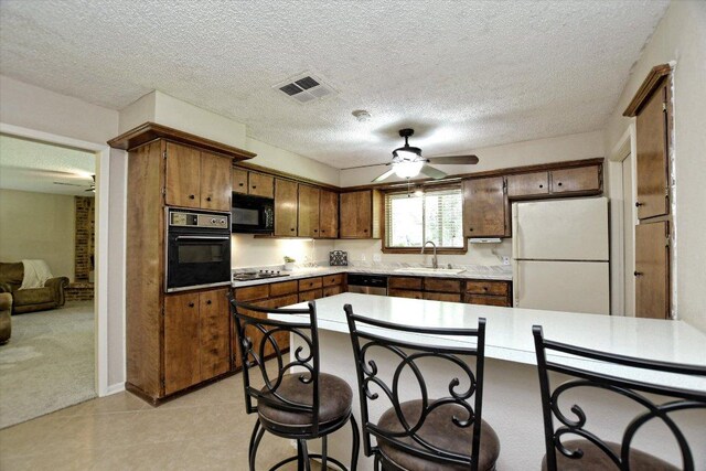 304 White Wing Way, Round Rock, TX 78664 - kitchen with black appliances, ceiling fan, a sink, light countertops, and a kitchen breakfast bar