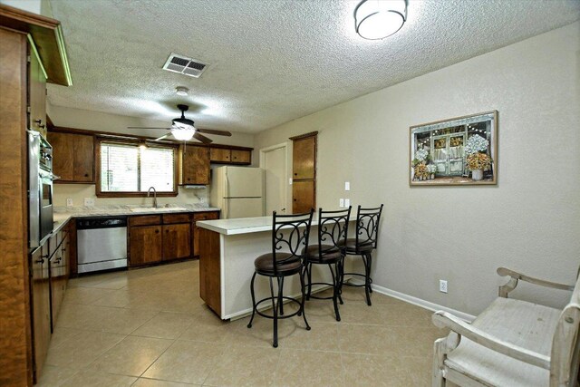 304 White Wing Way, Round Rock, TX 78664 - kitchen featuring appliances with stainless steel finishes, a peninsula, a sink, light countertops, and a kitchen breakfast bar