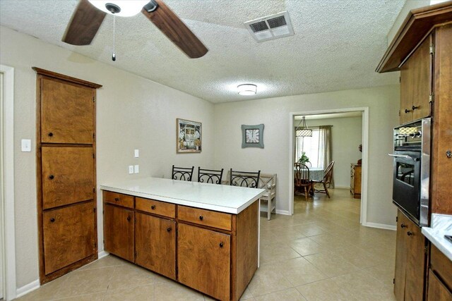 304 White Wing Way, Round Rock, TX 78664 - kitchen featuring oven, light countertops, a peninsula, brown cabinets, and light tile patterned floors