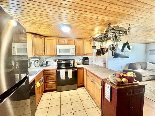1415 Bee Ln, Tow, TX 78672 - kitchen with white microwave, stainless steel electric range oven, a peninsula, light countertops, and wood ceiling